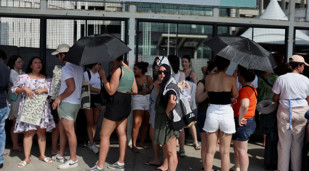 Fãs se protegem do sol enquanto aguardam em fila do lado de fora do estádio onde acontece o show da Taylor Swift no Rio de Janeiro, em meio a altas temperaturas. REUTERS/Pilar Olivares. Fonte: CNN