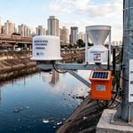 Agente da Defesa Civil e técnicos instalando e inspecionando sensores de monitoramento pluviométrico e nível de rio com conectividade IoT
