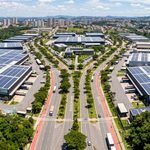 Vista aérea de Distrito Industrial Sustentável com telhados equipados com painéis solares, áreas verdes de preservação e galpões fabris modernos