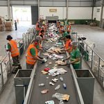 Integrantes de cooperativa de catadores de materiais recicláveis trabalhando em centro de triagem moderno equipado pela prefeitura